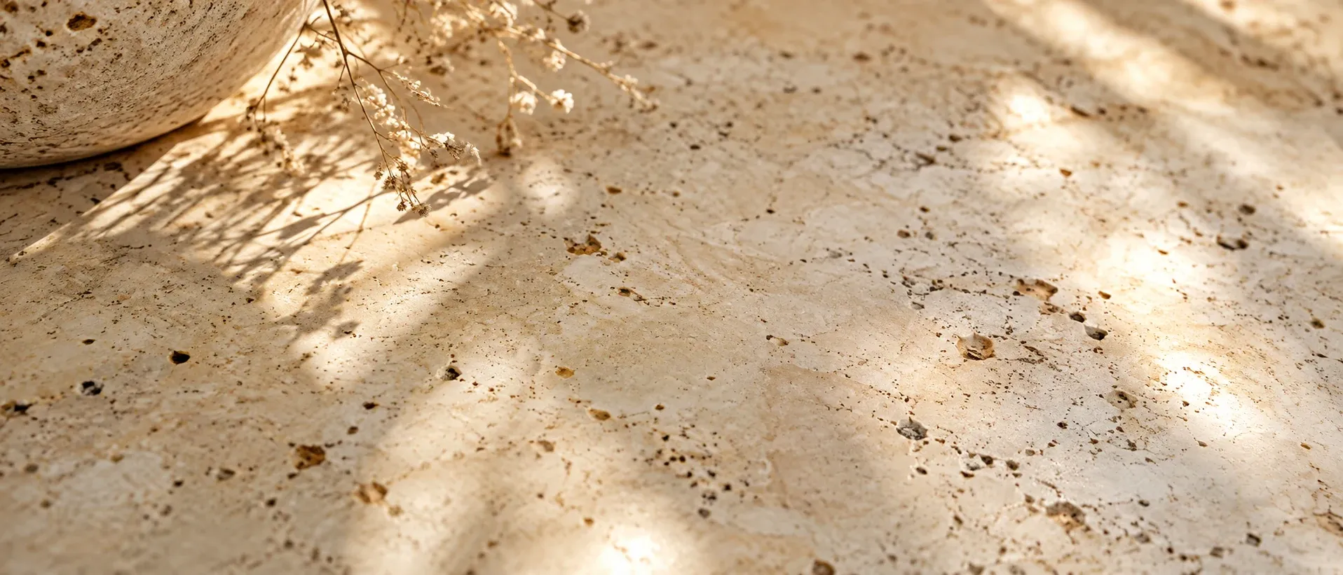 Scattered flecks of darker tone across pale stone