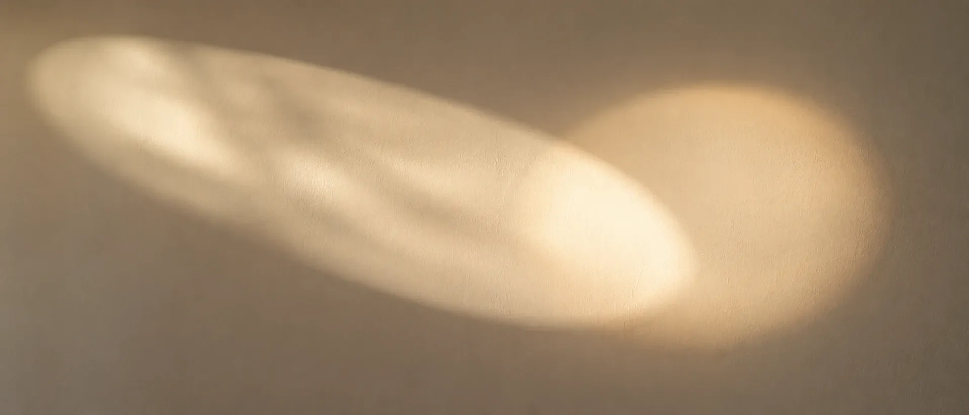 An elongated pool of warm light on a pale wall